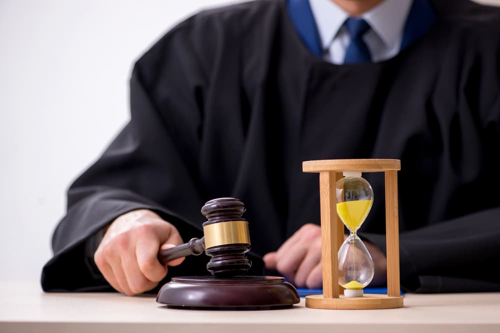 Male judge with gavel in hand and sandglass on the table
