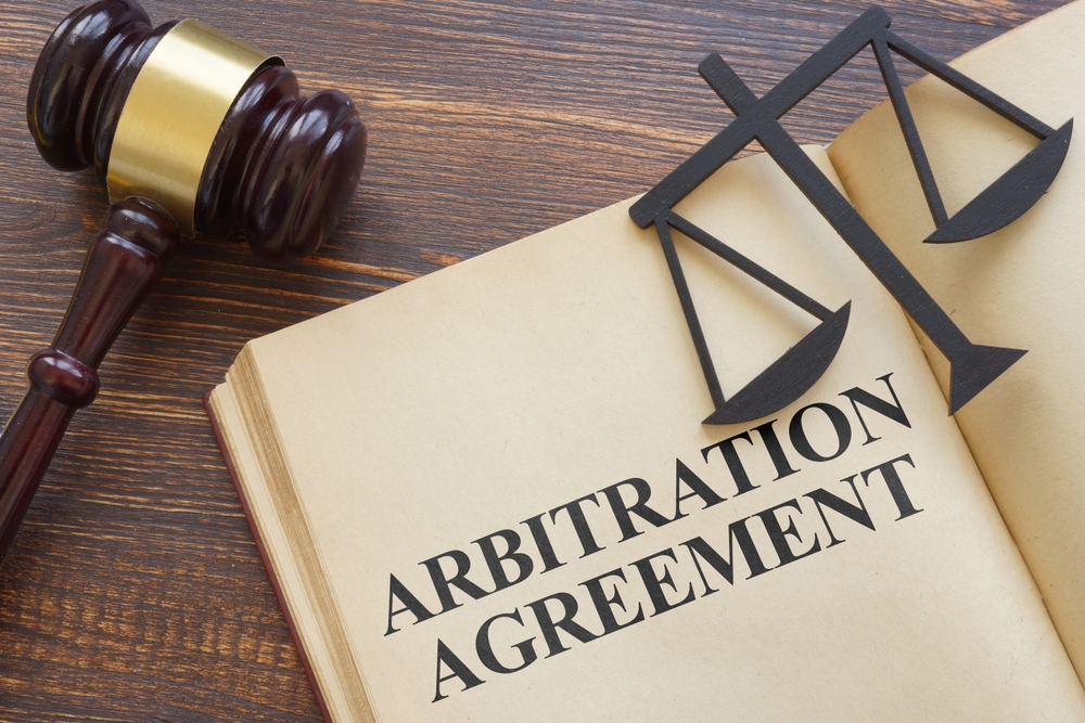 Book labeled arbitration agreement with gavel and scales of justice