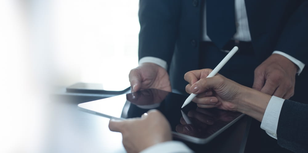 Two professionals in suits signing a document on a tablet during an arbitration proceeding in Washington