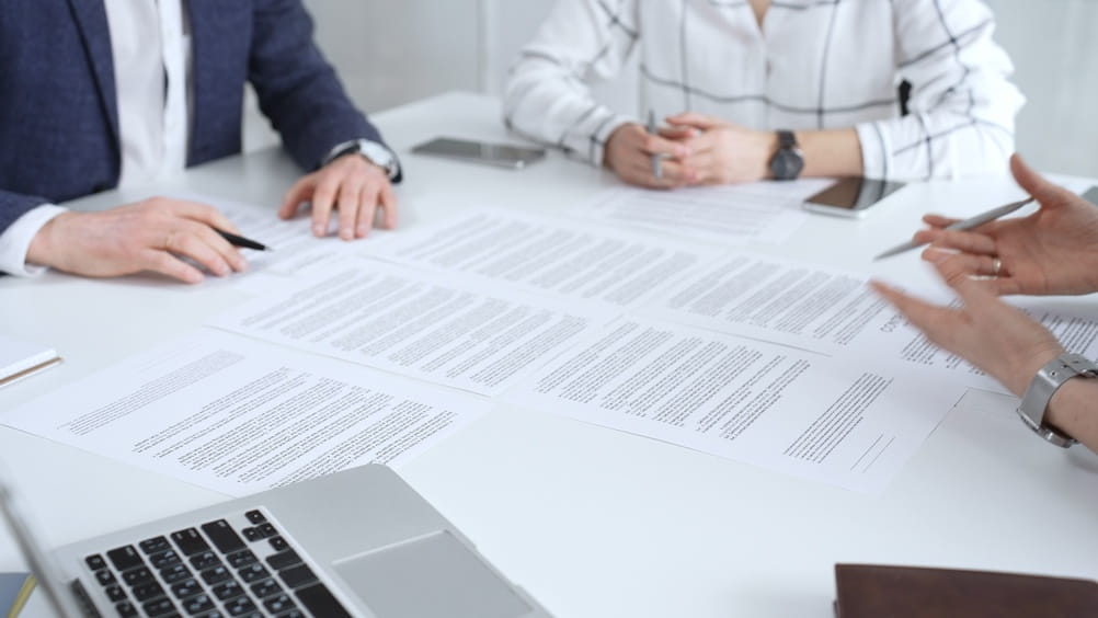 Multiple parties reviewing arbitration documents spread across a conference table in Washington
