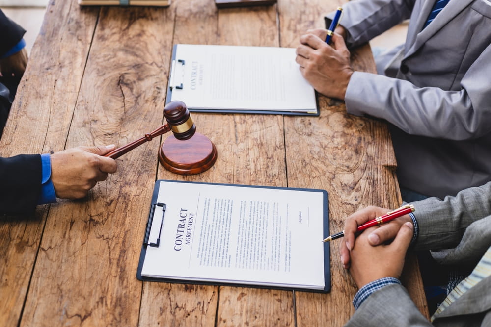 Parties reviewing contract agreement documents with a gavel on the table during a mediation settlement session in Washington